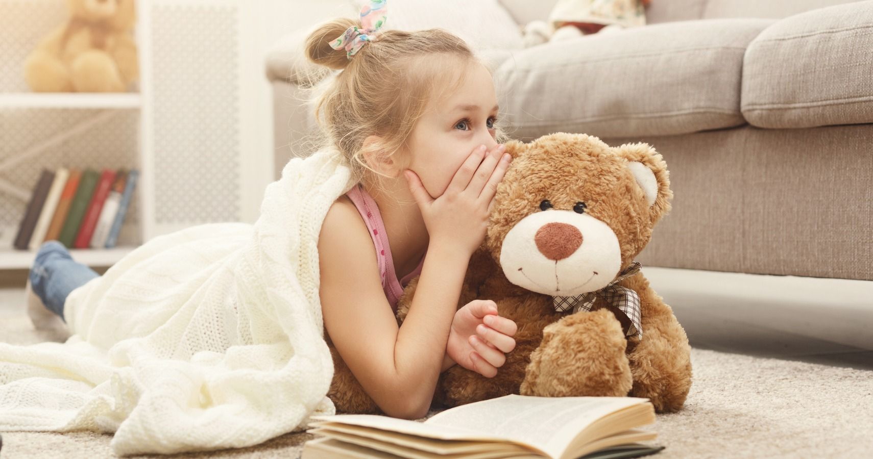 girl whispering to stuffed bear