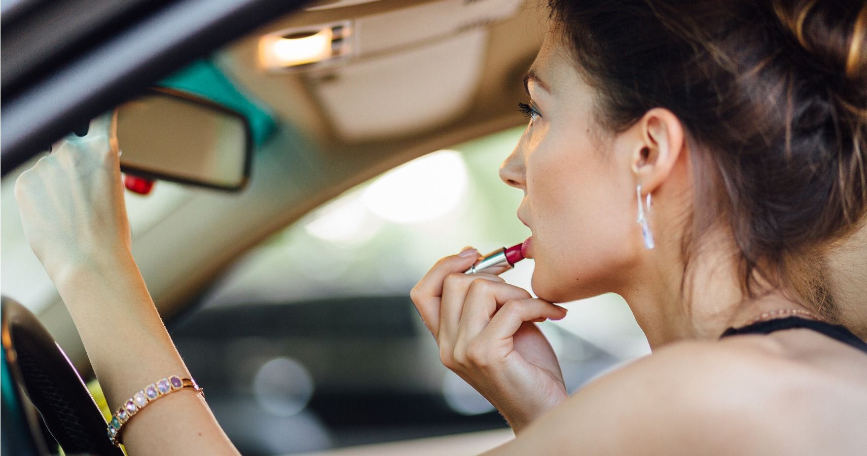 woman putting lipstick on in the car