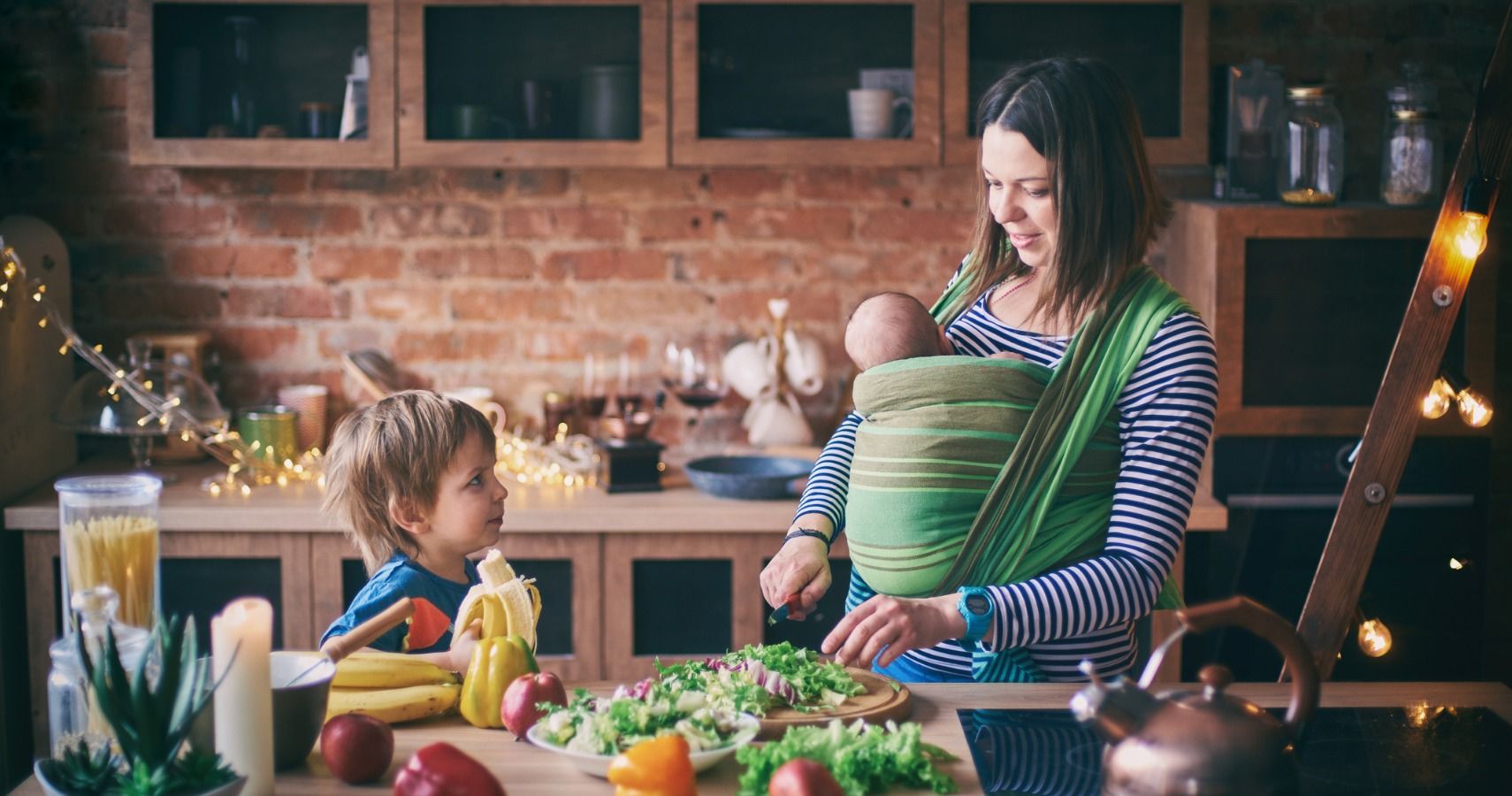 mom cooking with son and baby carrier