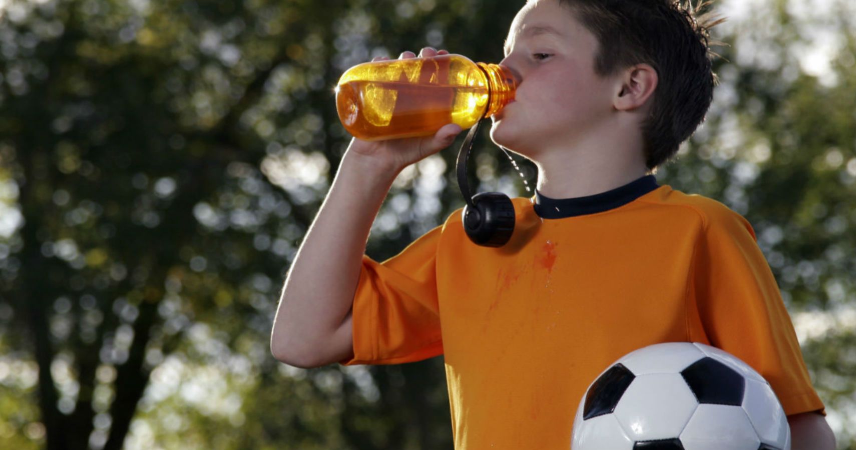 Child playing soccer drinking sports drink