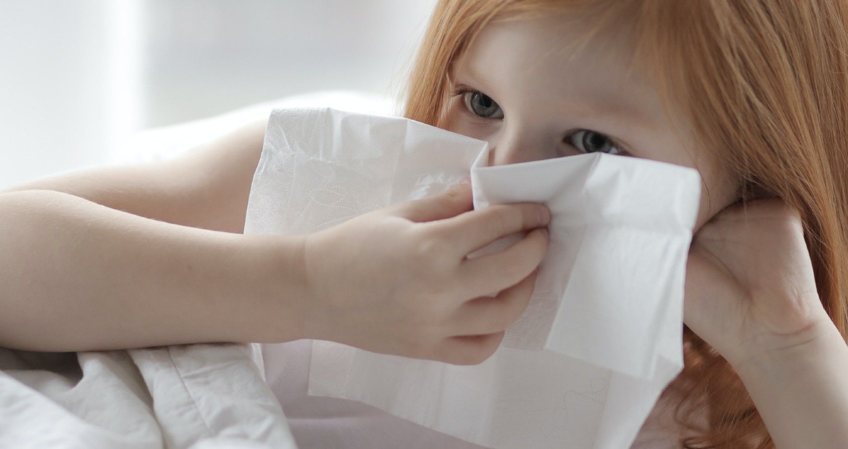 A child with a tissue up against her nose