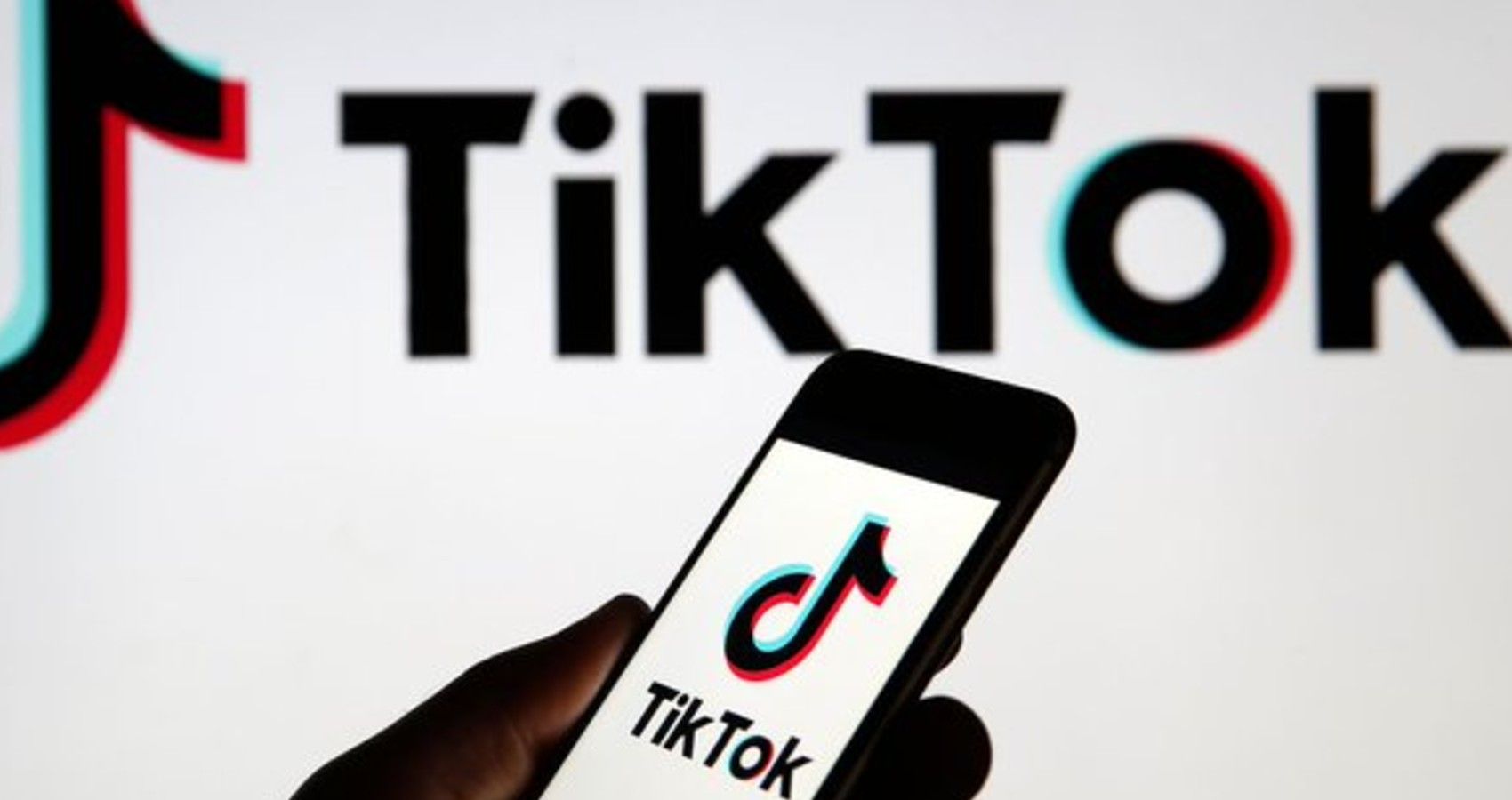 A picture of a hand holding a phone with the TikTok app and background
