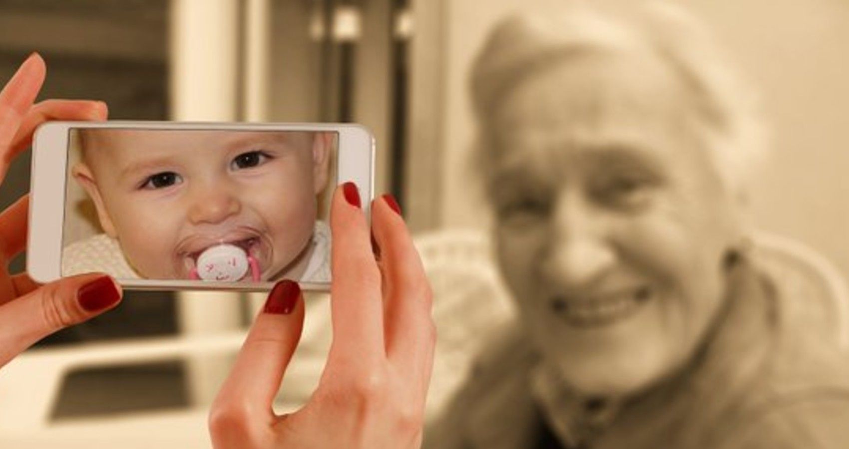 A woman holding up a cell phone with a picture of a baby on it to an older woman