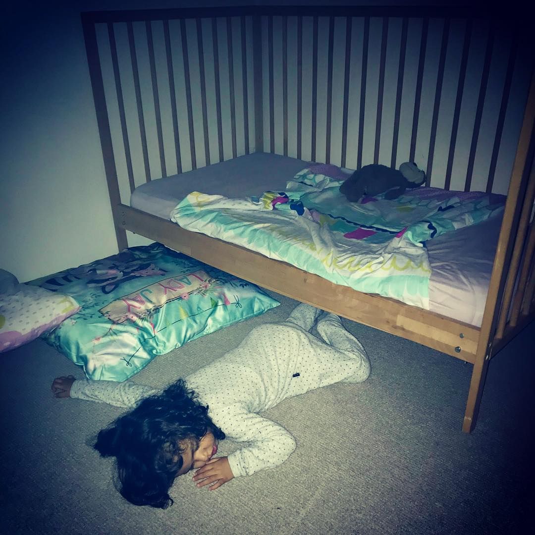 A child sleeping on the floor next to her bed