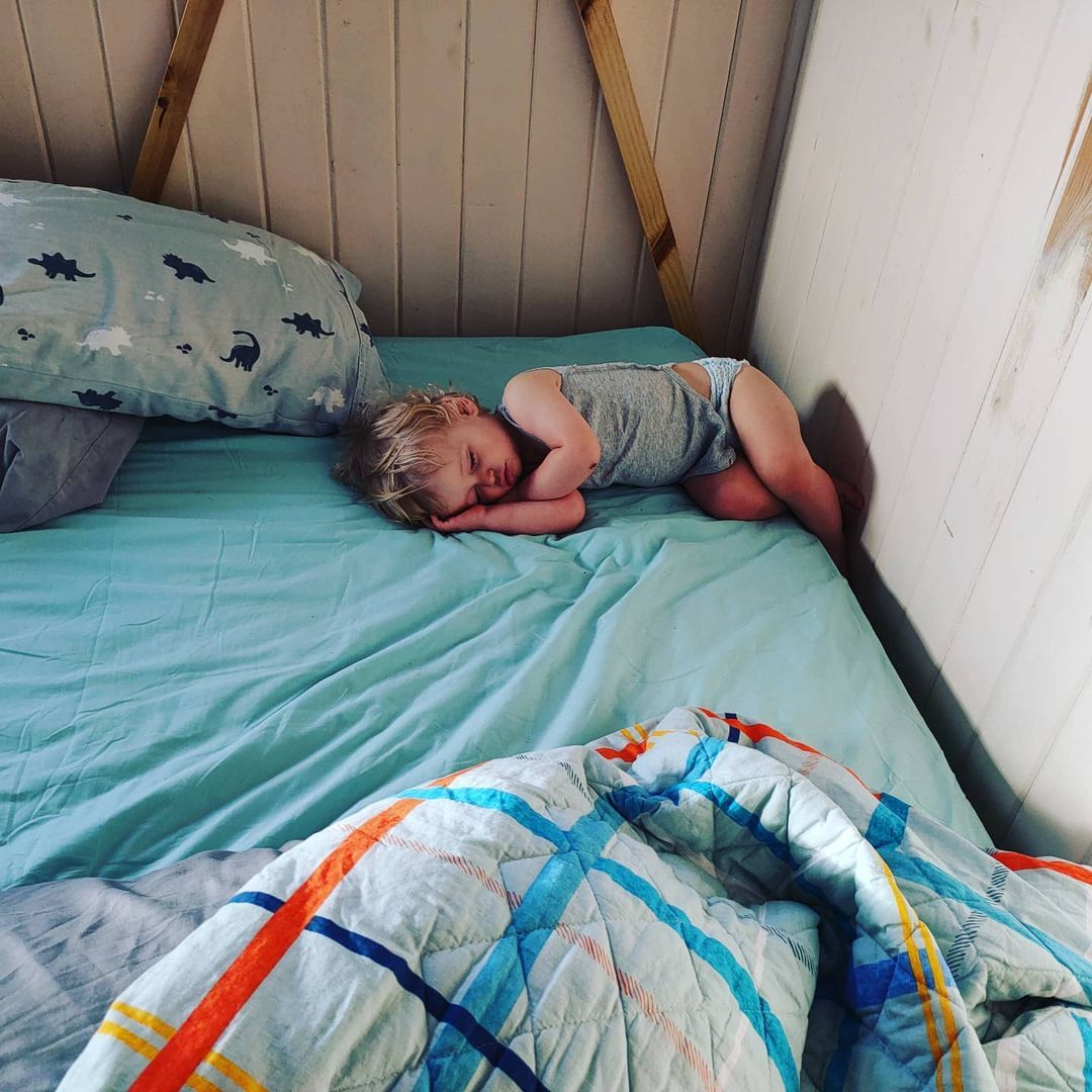 A toddler sleeping in an awkward position in bed