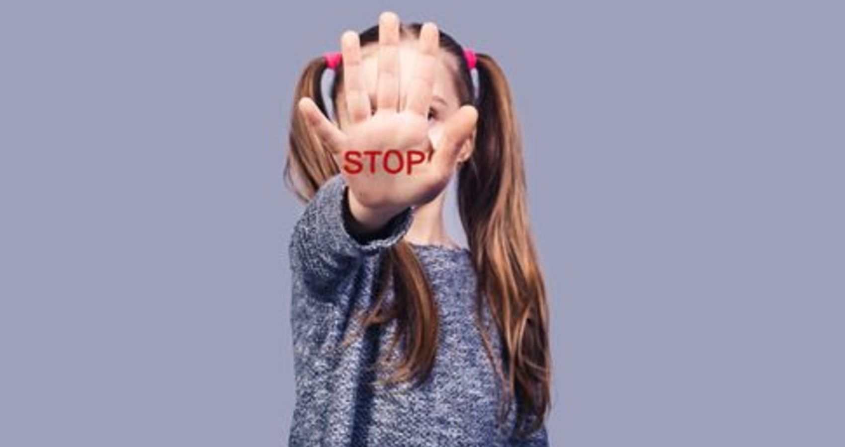 A child holding out her hand that says stop on it