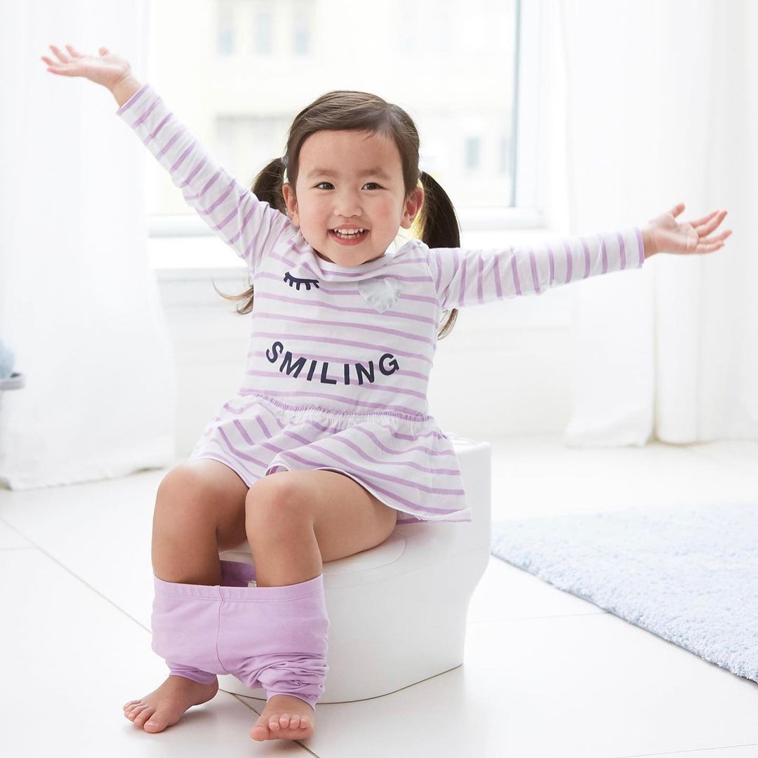 A little girl with her arms out on the potty