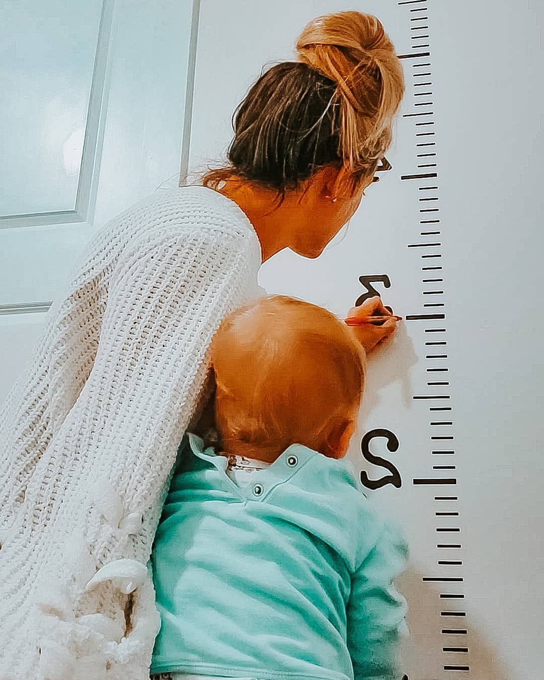 A mom marking on a growth chart how much her child has grown