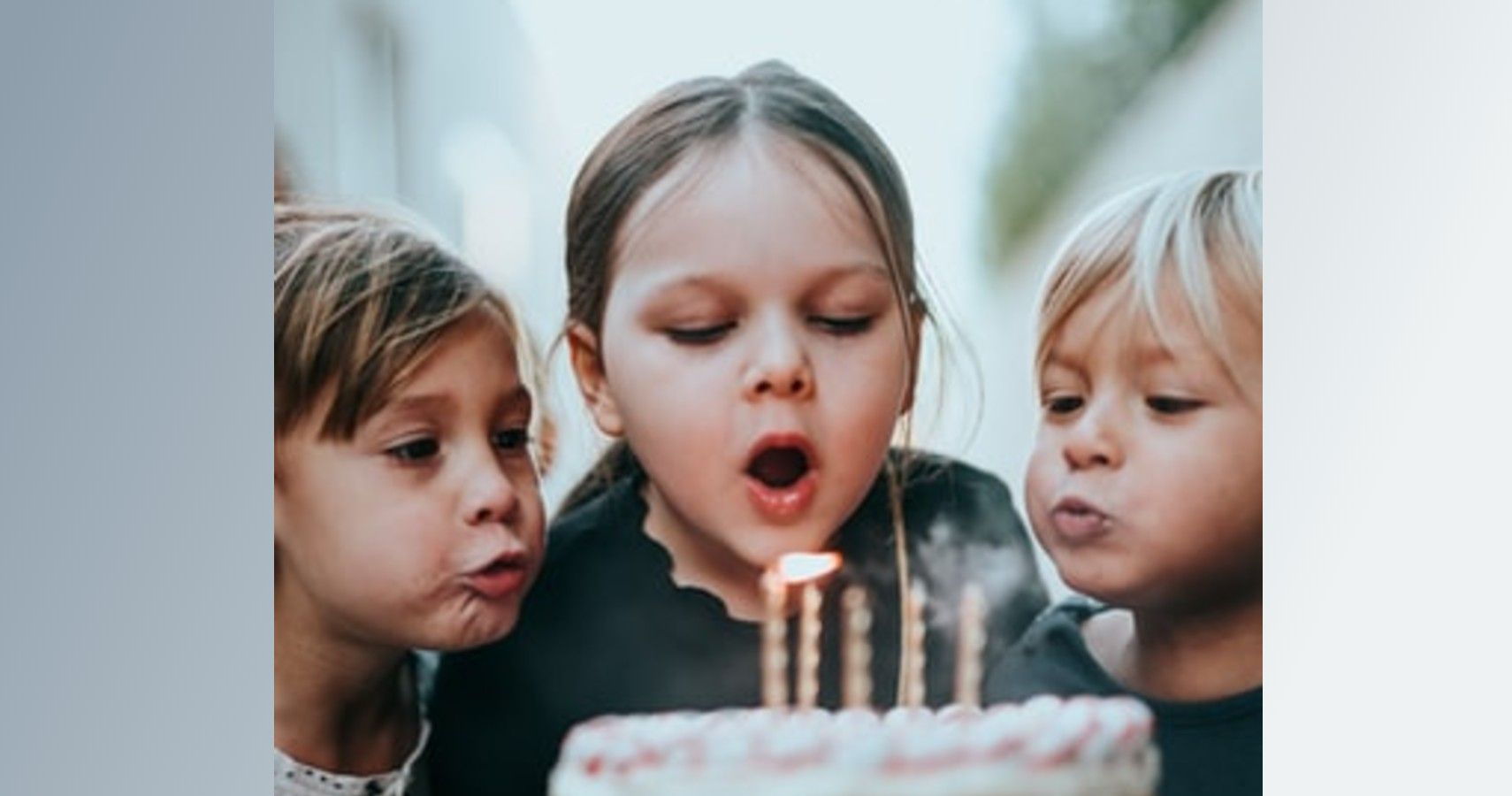Children blowing out candles on birthday cake