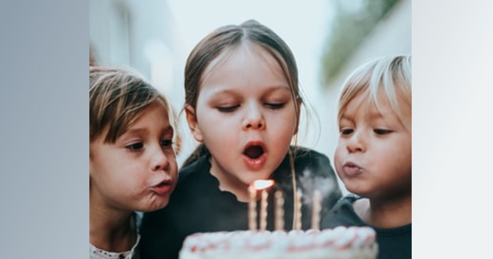 kids blowing out birthday cake candles