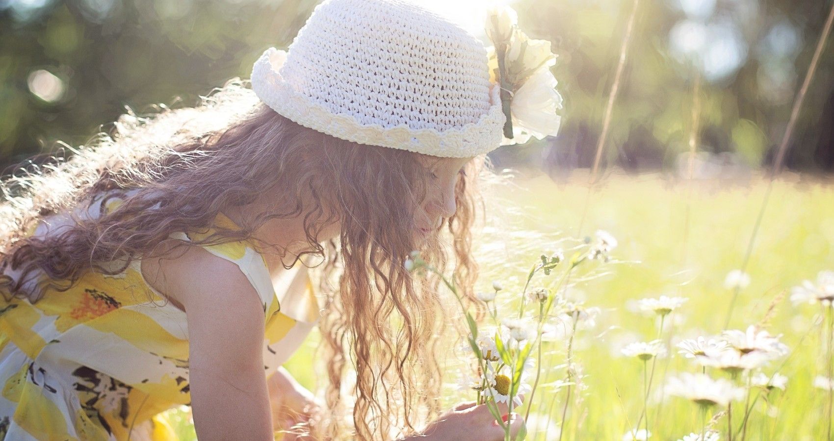 A child smelling flowers outside in the sun