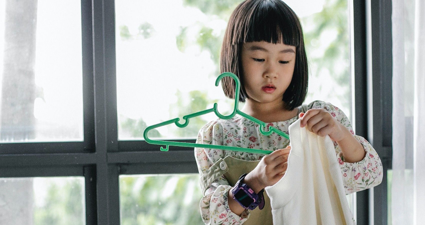 A child putting clothes on a hanger