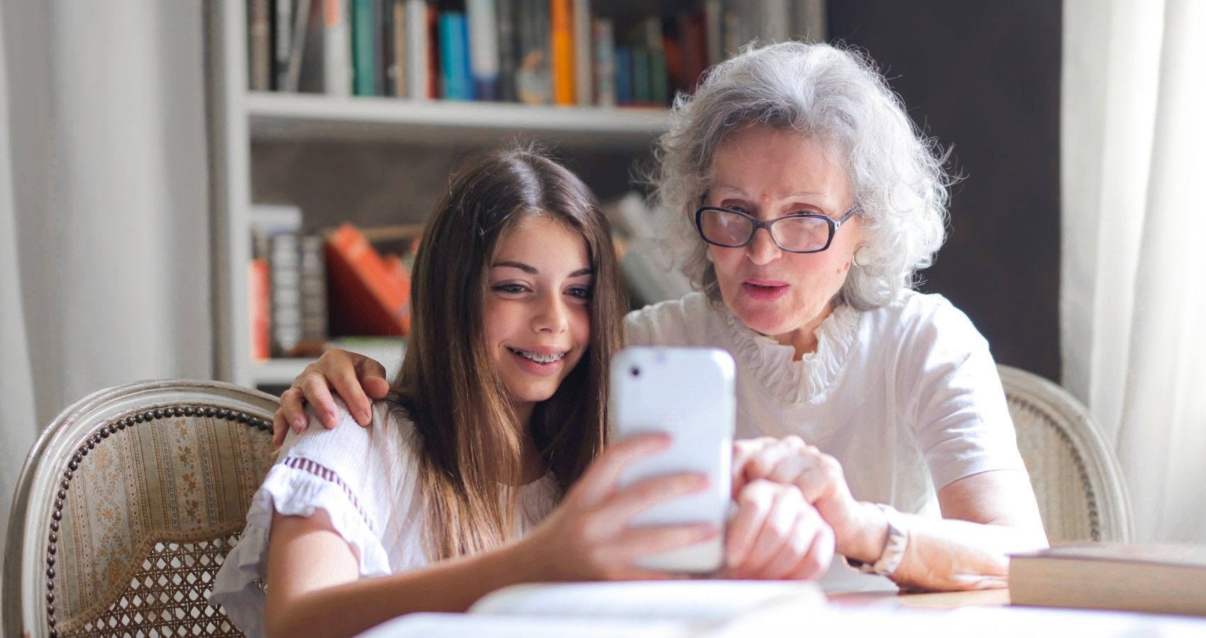 A grandmother sitting with her granddaughter looking at the cell phone