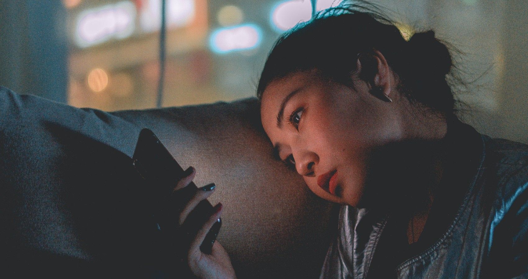 A teenager sitting and looking on her phone
