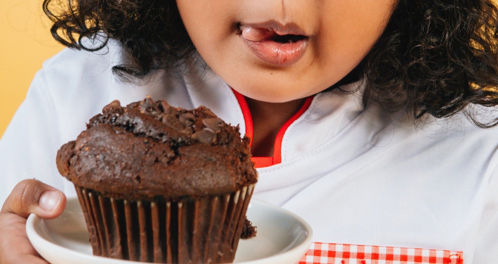 A child holding up a chocolate cupcake