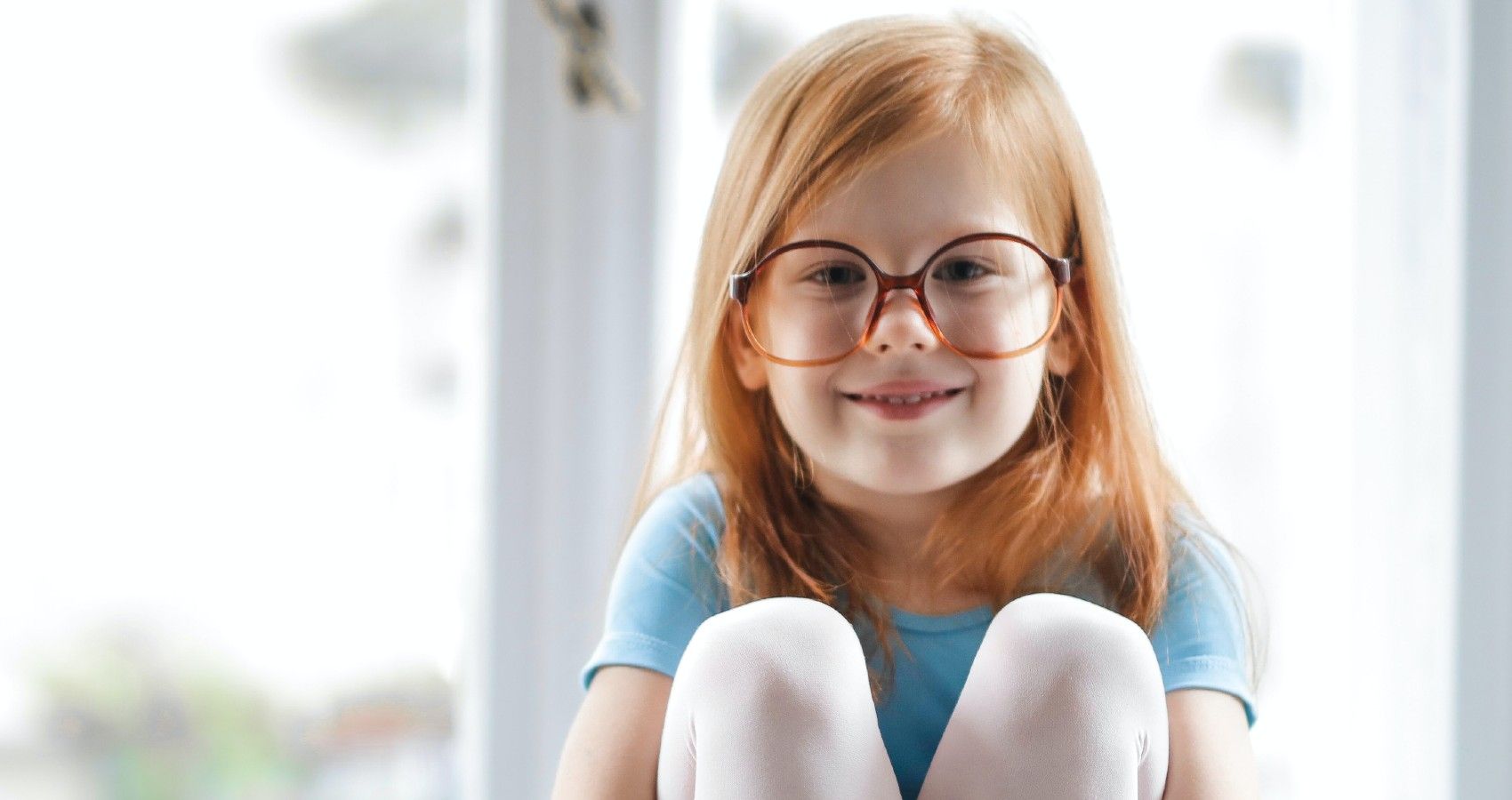 A child with red hair and wearing glasses