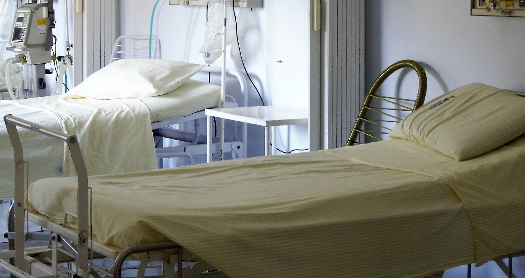 An empty hospital room with a row of beds in it