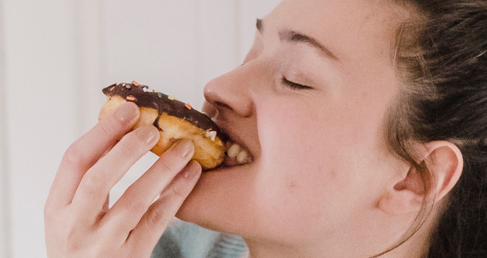 A woman eating a chocolate donut