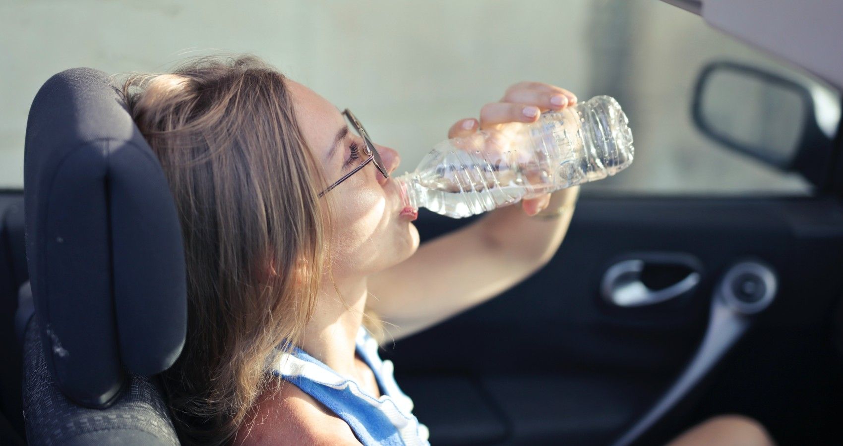 A teenager driving a car while drinking water