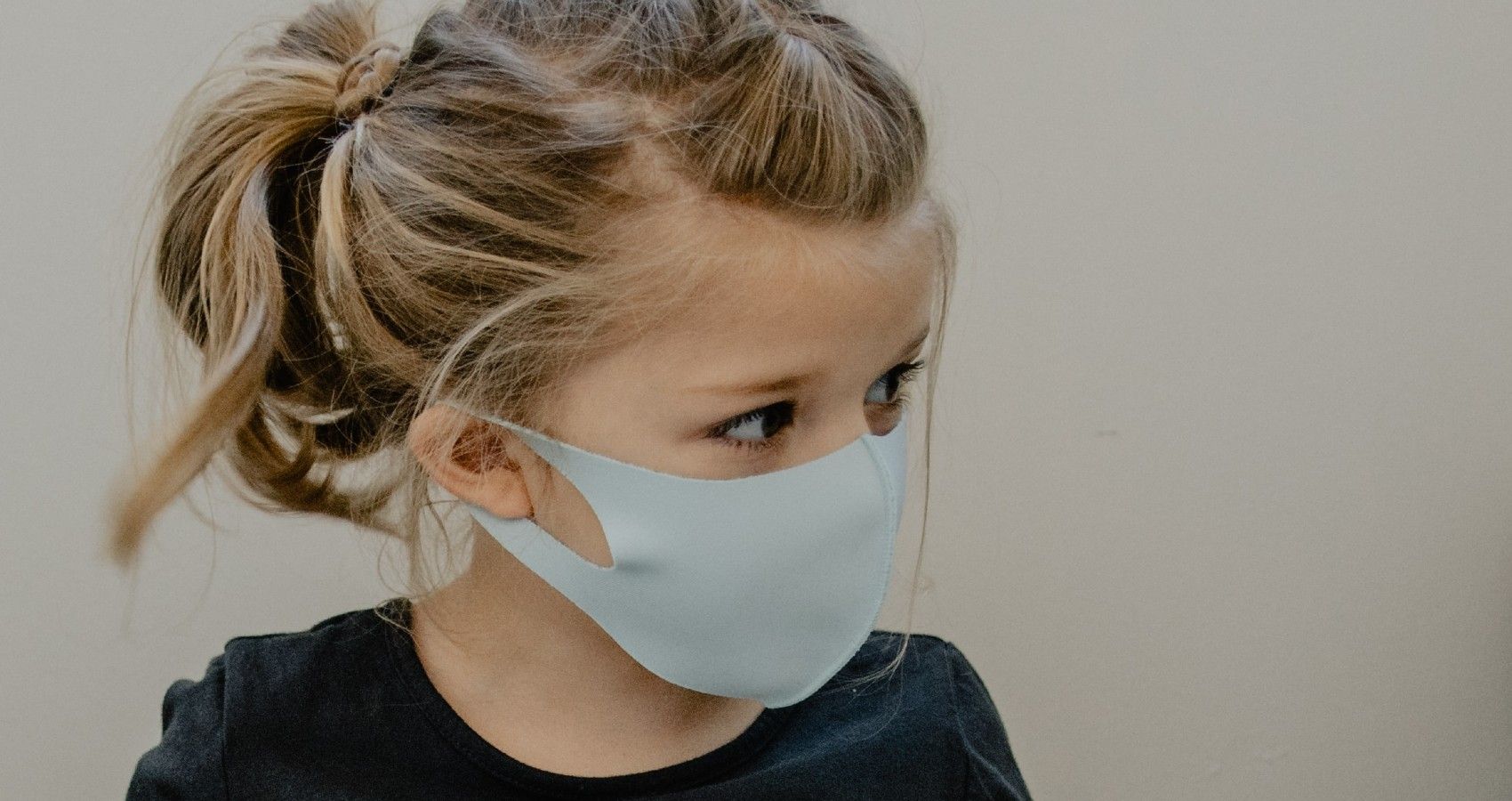 A young girl sitting inside with a face mask on