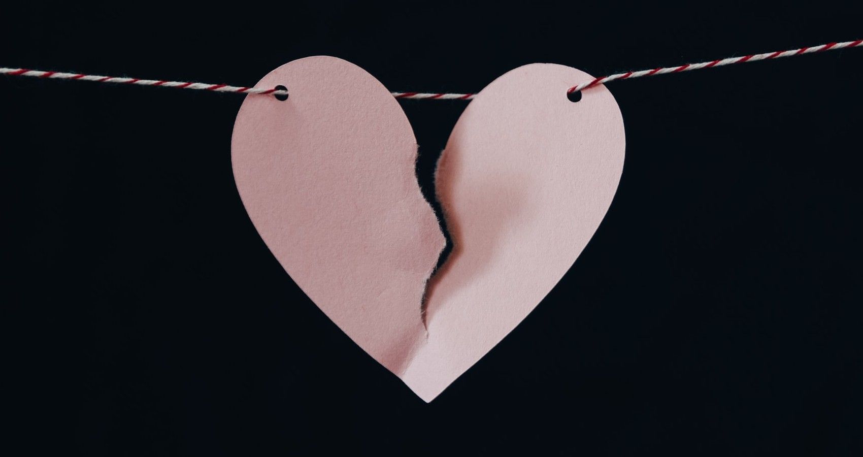 A paper heart that is hanging on a string and ripped
