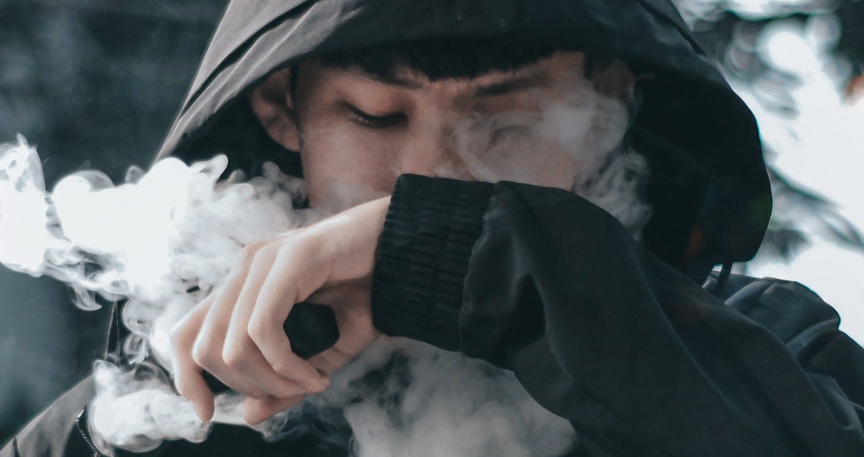 A Youh Vaping In A Black Sweater With Smoke