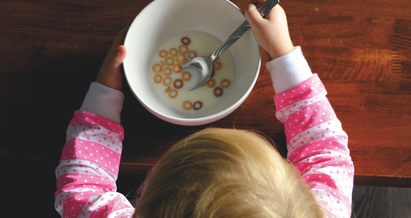 A Child Looking Over A Bowl Of Cereal