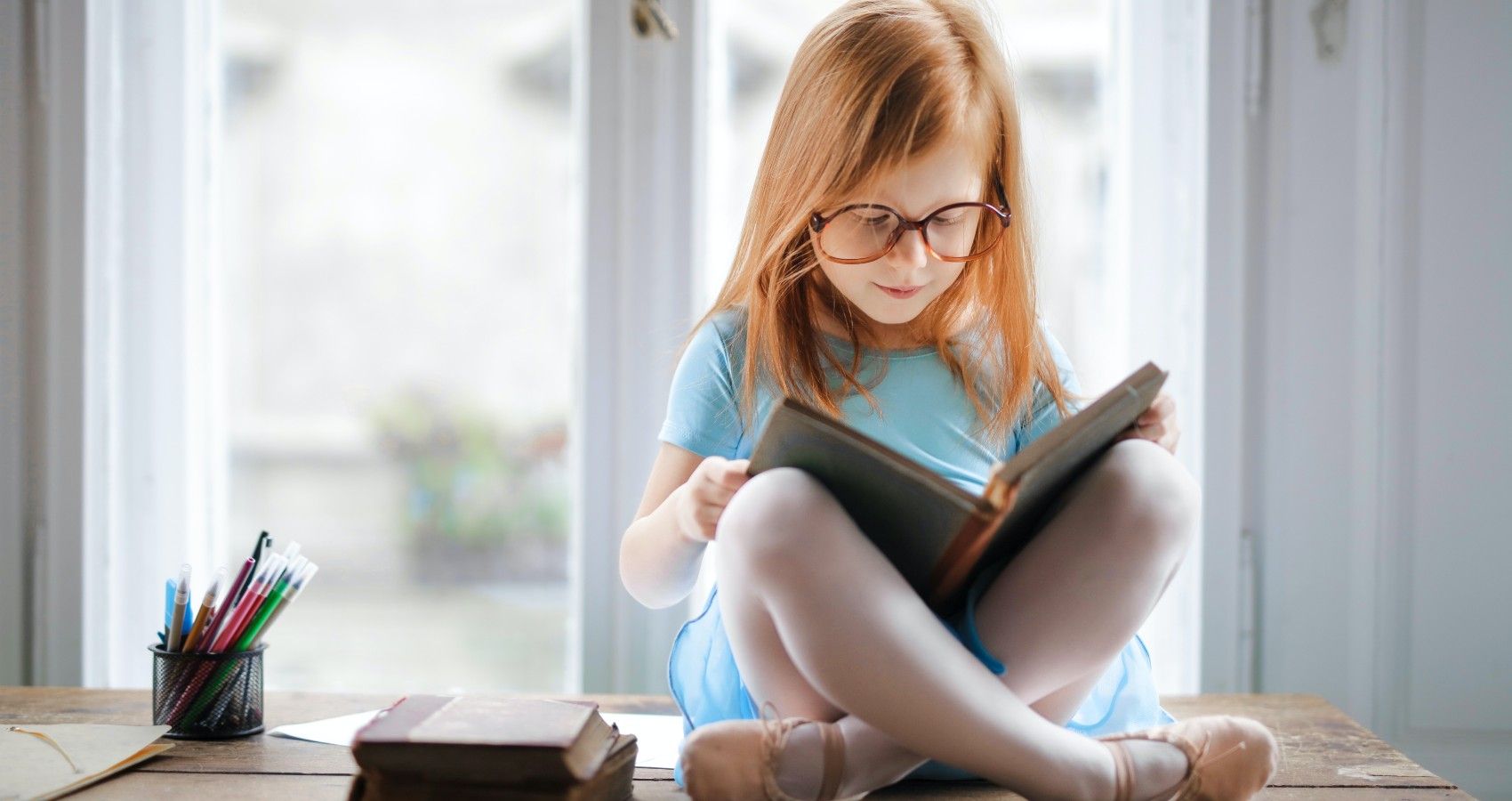 A Young Girl Sitting And Reading A Book With Extra Spaces
