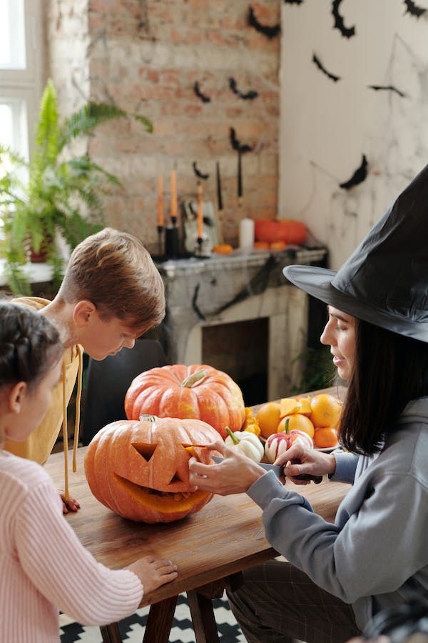 Mom carving pumpkin with kids