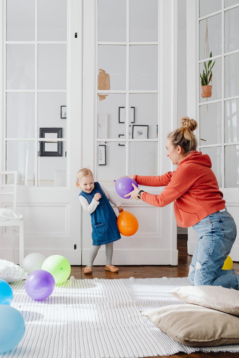 Mother and daughter playing with balloons in home 