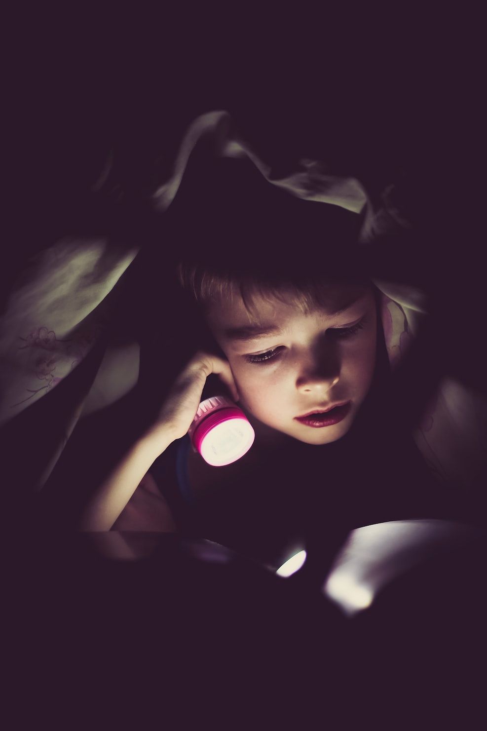 Boy reading with flashlight