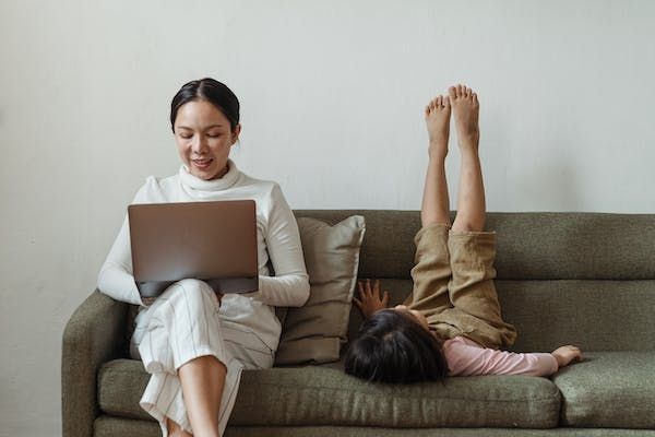 Mom on computer with child sitting on couch