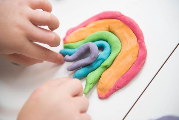 Child making rainbow with playdoh