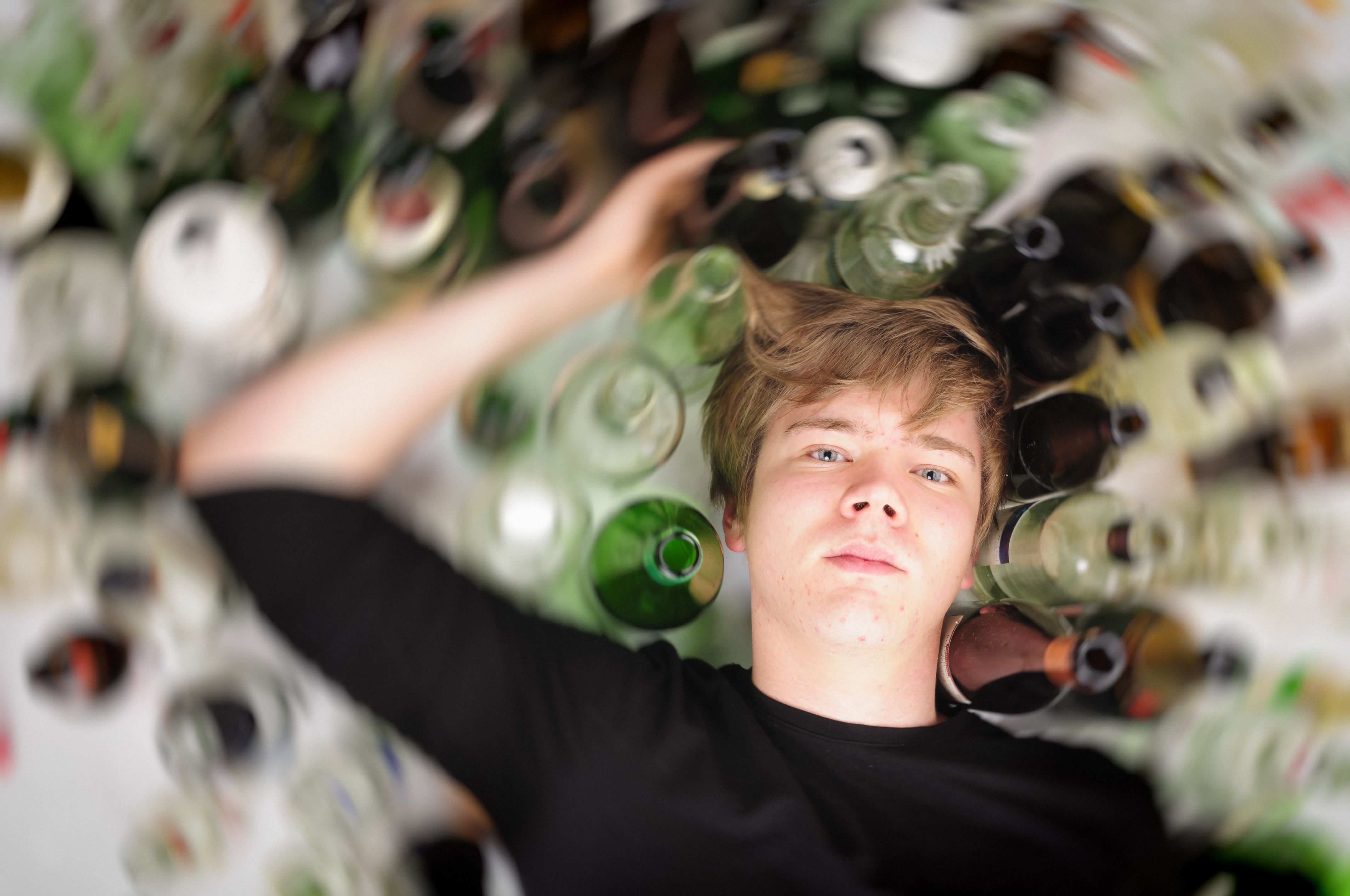 teenage boy surrounded by glass bottles