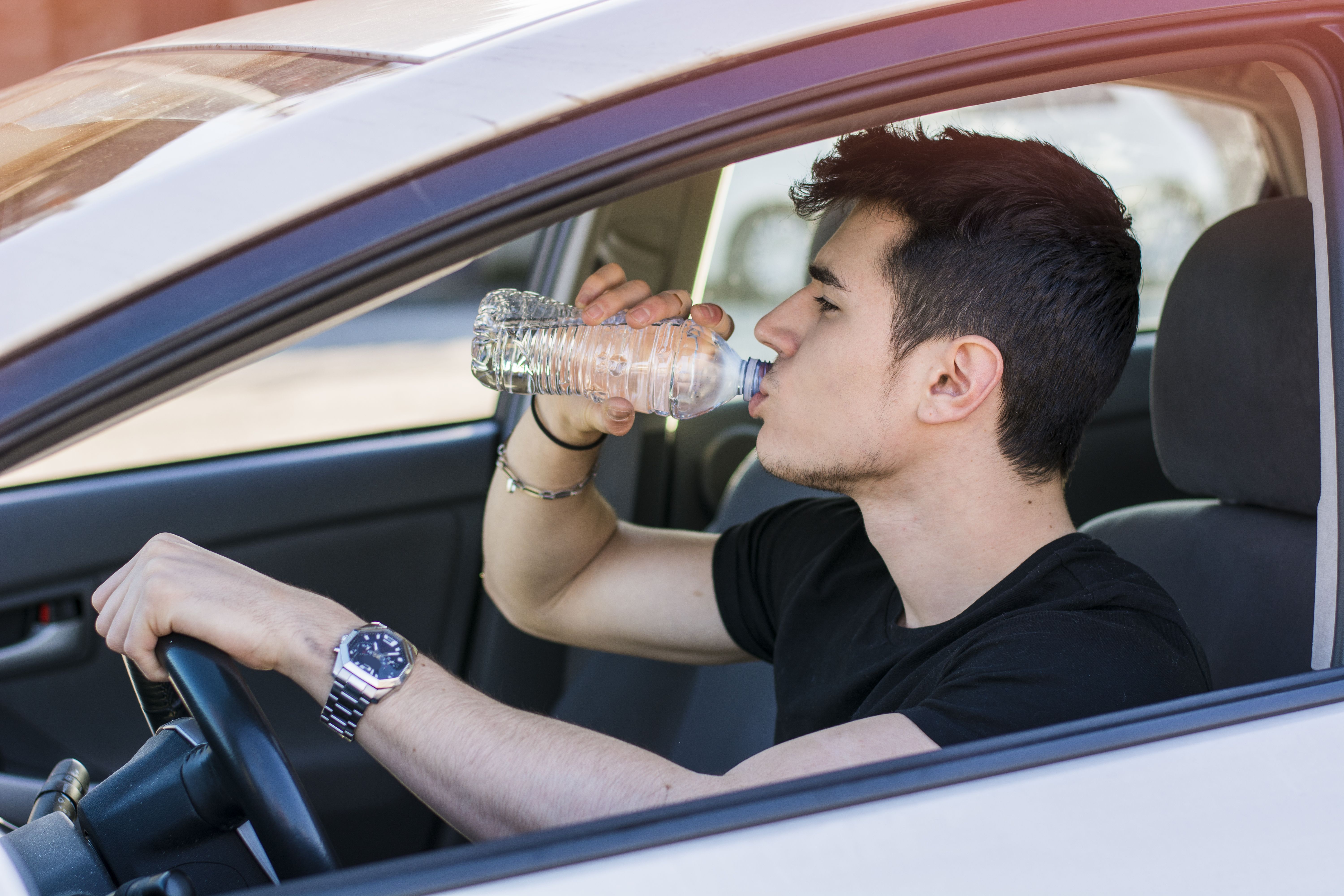 teen drinking water in car