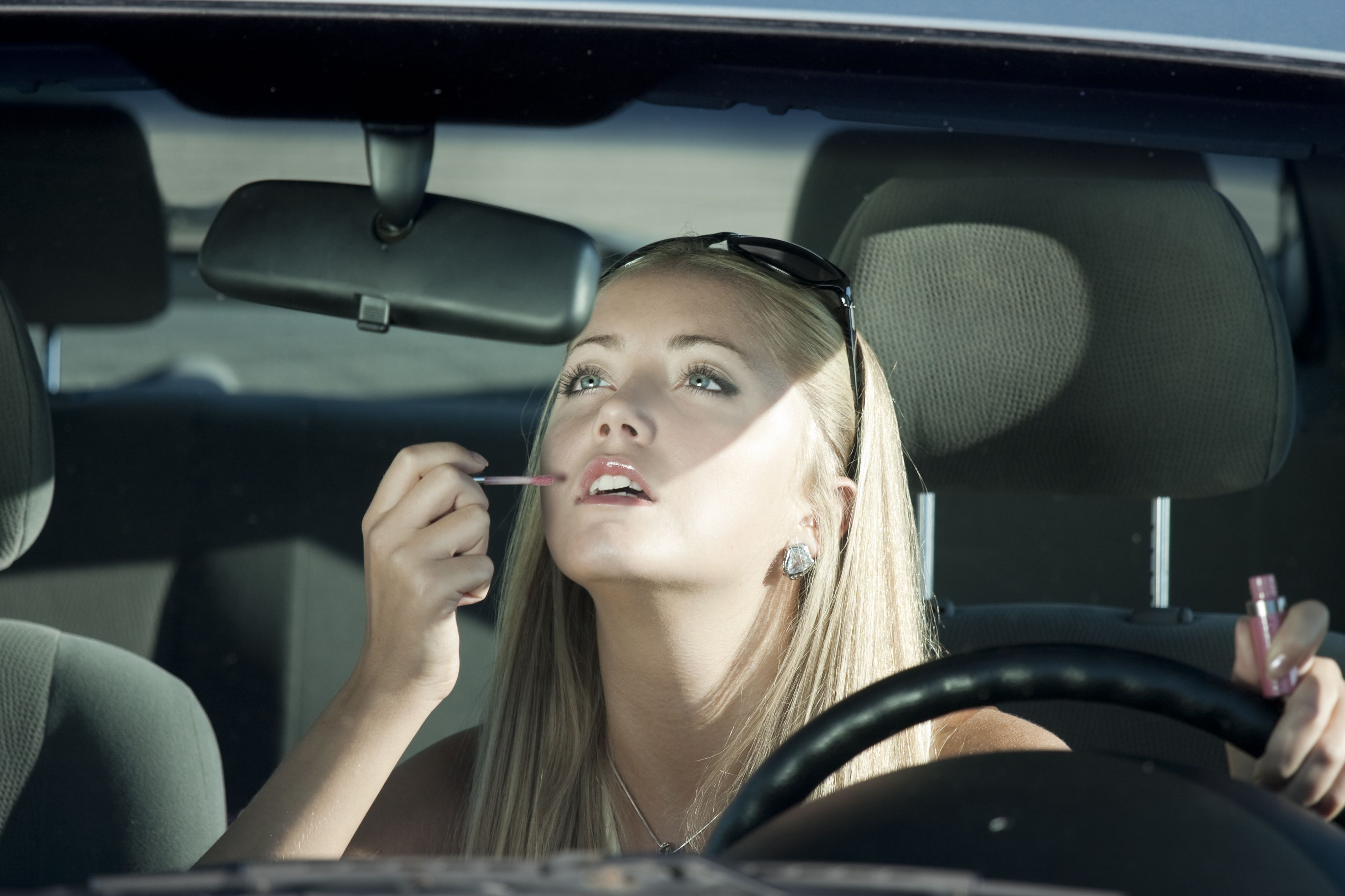 teen putting lip gloss in car