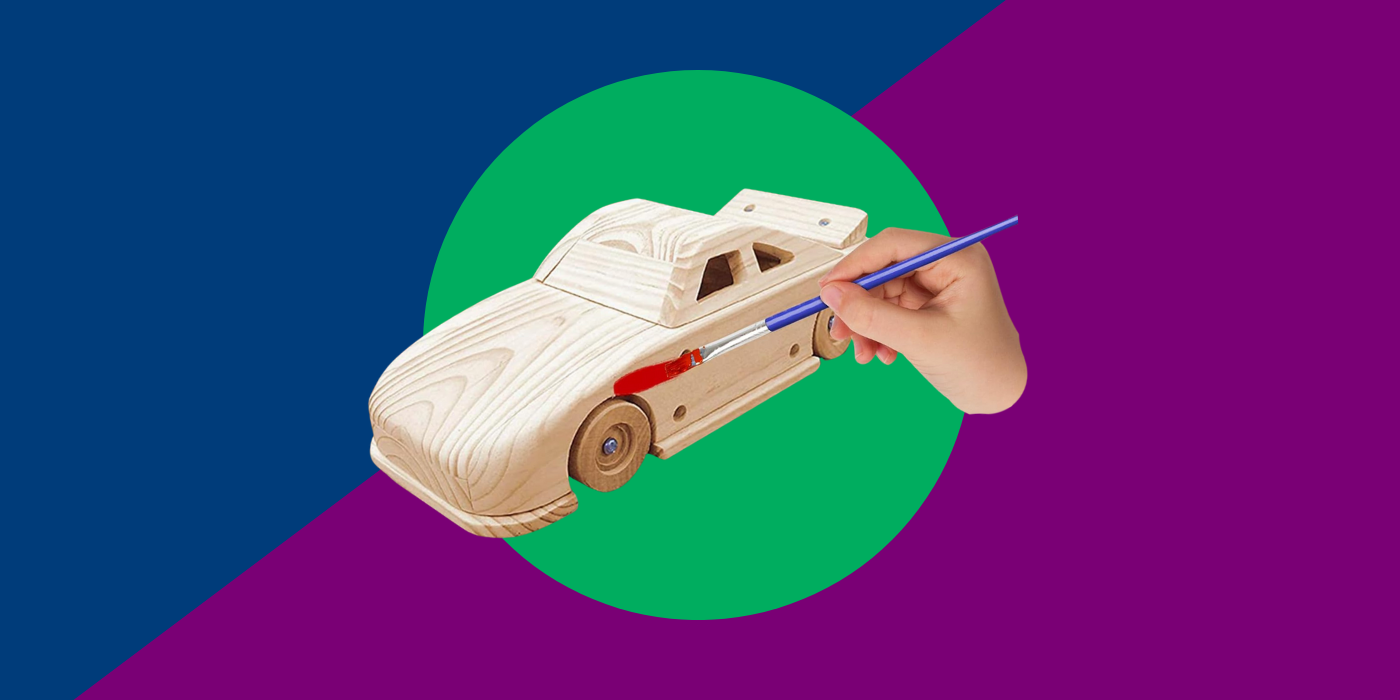 Blue, green and purple background with a wooden model car and a hand with a paintbrush